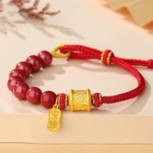 Om Mani Padme Hum red string bracelet with cinnabar beads and sterling silver charm - flat lay overhead view