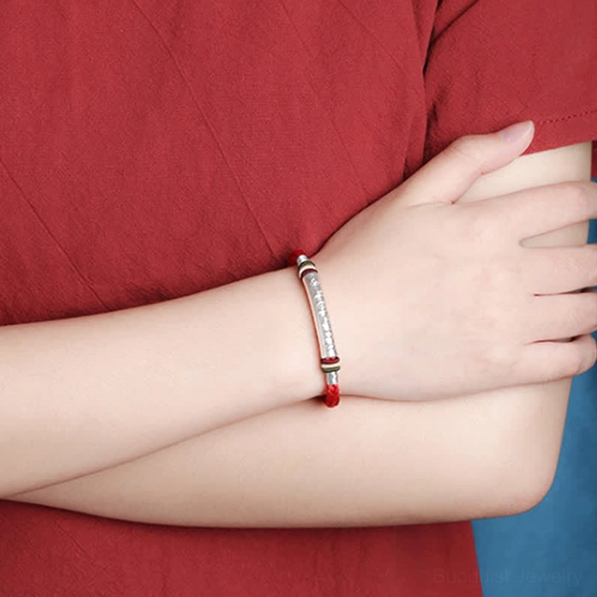 Om mani padme hum spiritual bracelet on right forearm side view displaying adjustable tassel closure and braided red cord design