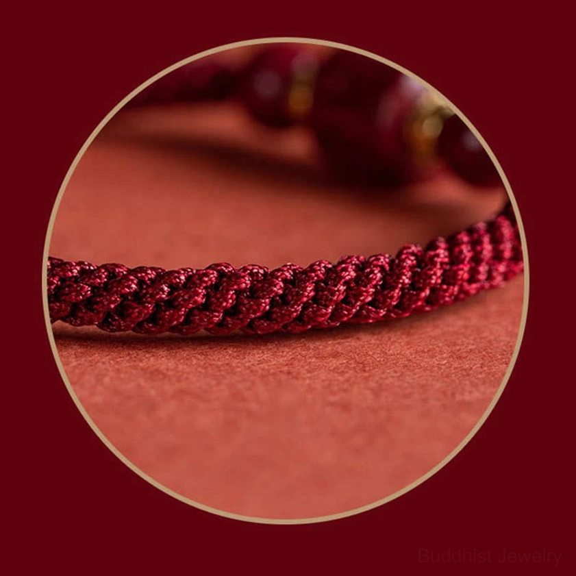Red string Buddhist bracelet featuring Om Mani Padme Hum engraved mantra bead with cinnabar gemstones and braided cord