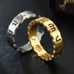 Couple wearing black and golden om mani padme hum titanium steel meditation rings with wavy band design on dark reflective surface