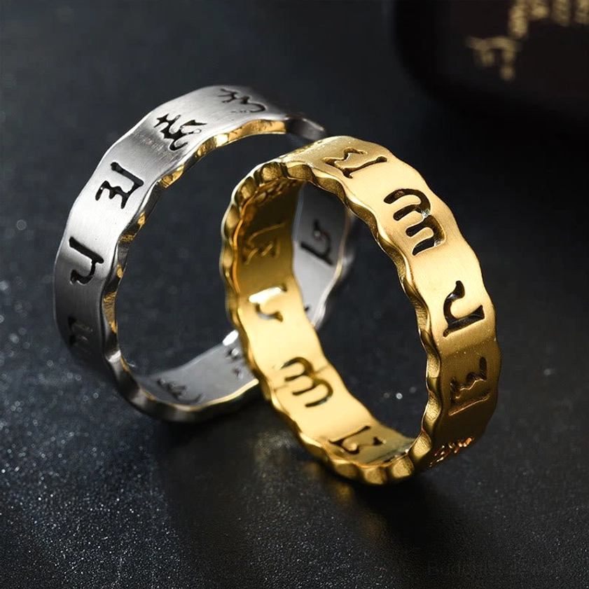 Couple wearing black and golden om mani padme hum titanium steel meditation rings with wavy band design on dark reflective surface