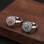 Om Mani Padme Hum adjustable copper ring in blue and red styles shown on dark wooden surface with vintage silver finish