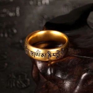 Om Mani Padme Hum adjustable Buddhist mantra ring with engraved Sanskrit characters in golden finish, close-up side view on dark wooden background