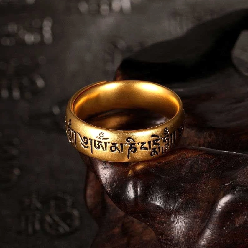 Om Mani Padme Hum adjustable Buddhist mantra ring with engraved Sanskrit characters in golden finish, close-up side view on dark wooden background