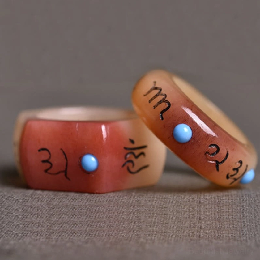 Two Buddhist mantra rings in different styles - round and hexagonal profiles with carved Om Mani Padme Hum and blue gemstone accents