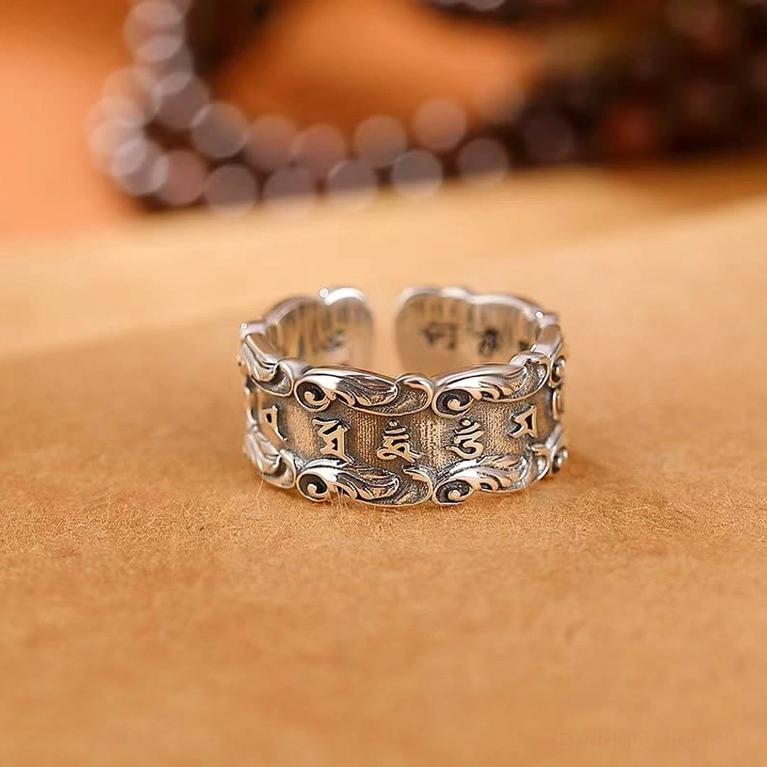 Six-syllable mantra adjustable ring top front view showing embossed Om Mani Padme Hum text and lotus floral motifs in vintage silver tone