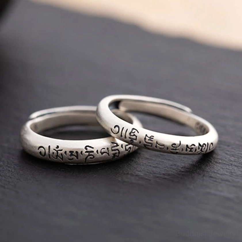 Two intertwined Om Mani Padme Hum sterling silver Buddhist mantra rings crossed placement oblique angle view