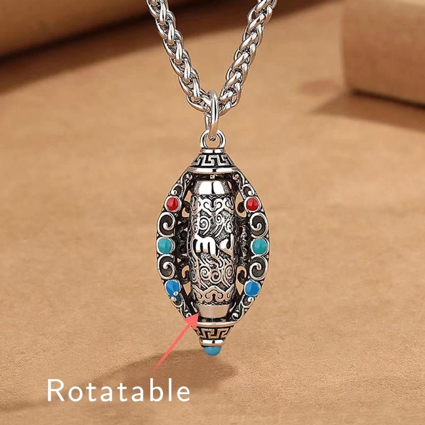 Om Mani Padme Hum rotatable Buddhist necklace pendant front view with turquoise and coral gemstone inlays on brown kraft paper background