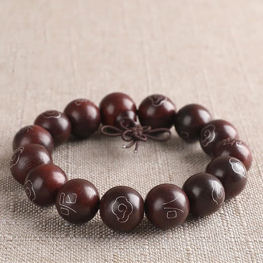 Red sandalwood Om Mani Padme Hum bracelet with distinct silver inlay patterns and central decorative tassel knot