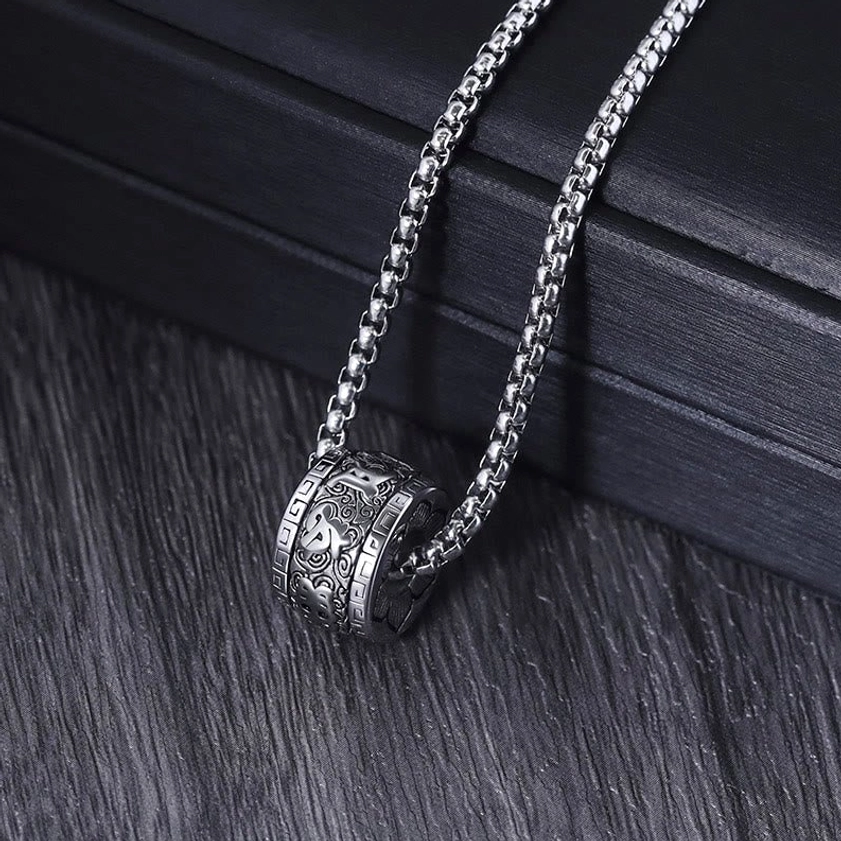 Silver Om Mani Padme Hum necklace with carved barrel pendant and wheat link chain, side view on black leather
