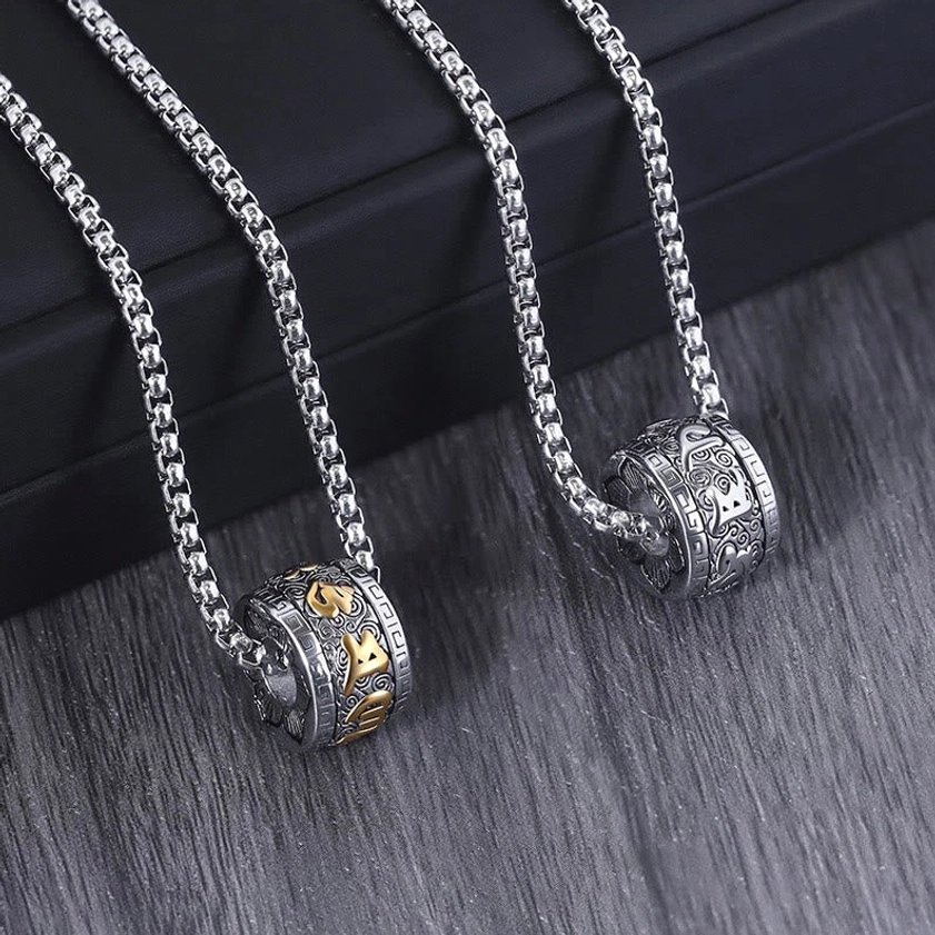 Pair of silver Om Mani Padme Hum necklaces with wheat chain, flat lay display on wooden table with black gift box