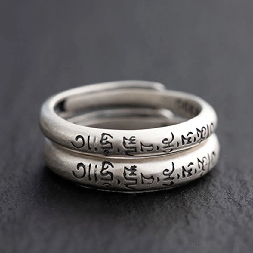 Two stacked Om Mani Padme Hum sterling silver Buddhist mantra rings top-down view showing engraved text detail