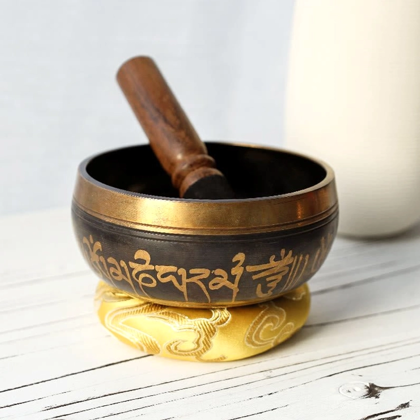 Handcrafted copper singing bowl with Om Mani Padme Hum engraving, wooden mallet, and silk meditation cushion