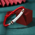 999 sterling silver om mani padme hum red string bracelet with engraved silver tube and colorful spacer beads on dark green studio background