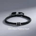 Om Mani Padme Hum sterling silver braided Buddhist string bracelet flat lay with engraved silver mantra bead