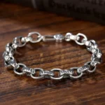 925 sterling silver Om Mani Padme Hum engraved Buddhist bracelet with lobster clasp, top-down view on dark wooden surface