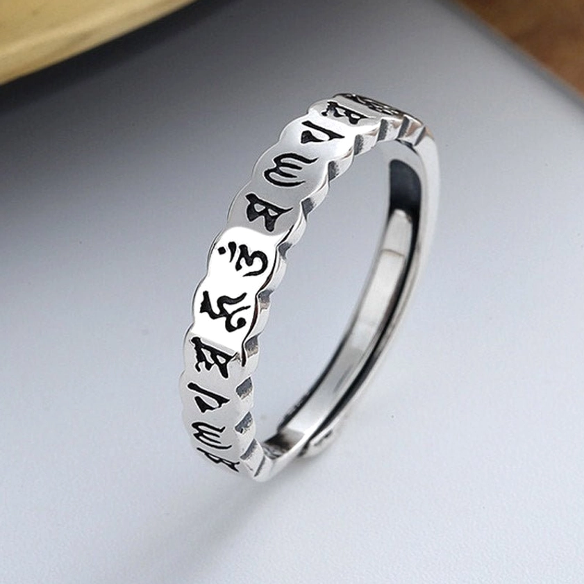 Om Mani Padme Hum sterling silver mantra ring - close-up oblique view showing engraved Sanskrit mantras with vintage silver finish on light background