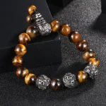 Om Mani Padme Hum bracelet with tiger eye beads and engraved titanium steel mantra beads, oblique top-down view on black textured display