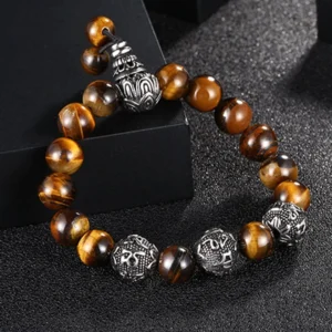Om Mani Padme Hum bracelet with tiger eye beads and engraved titanium steel mantra beads, oblique top-down view on black textured display