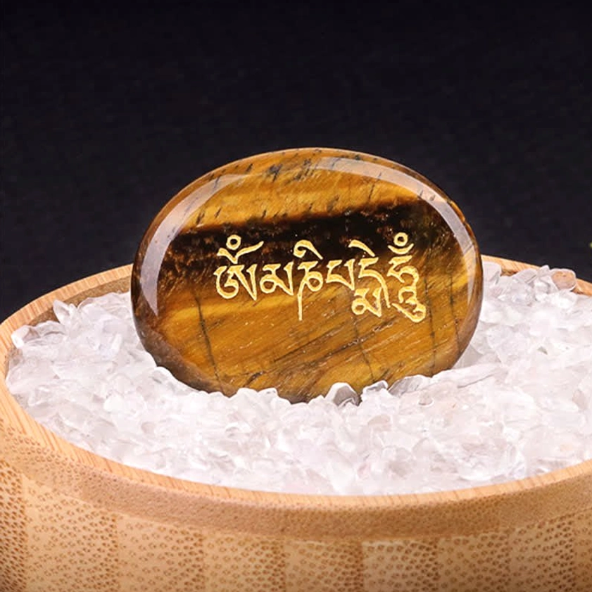 Om Mani Padme Hum tiger eye palm stone with golden Sanskrit text in wooden bowl