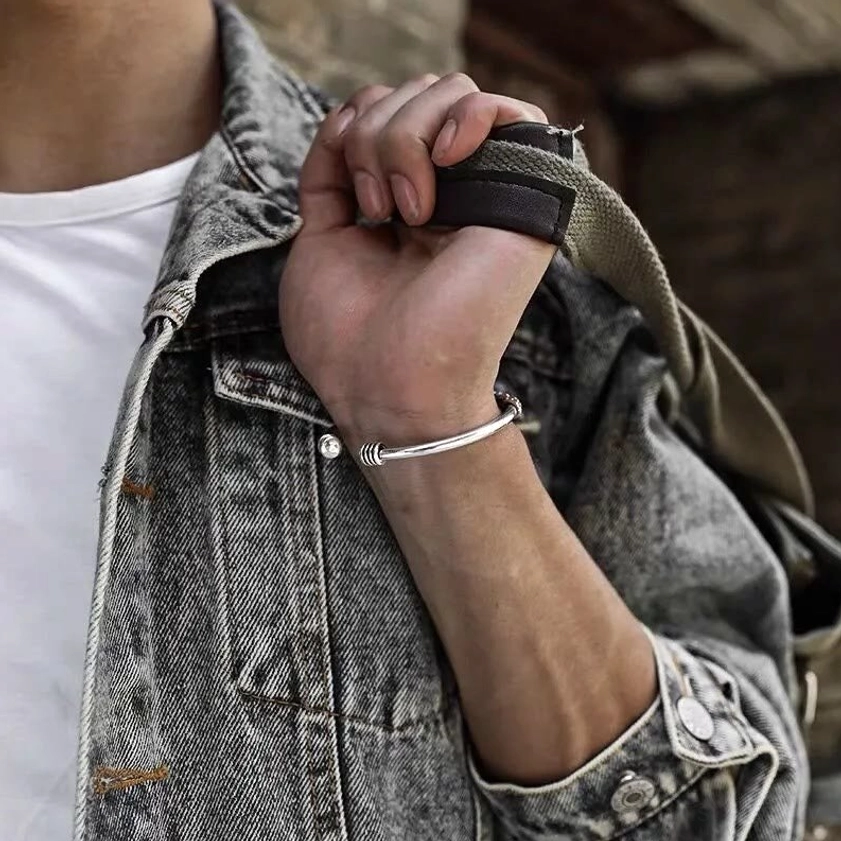Retro silver tone open cuff bracelet with engraved mantras worn with denim jacket showing understated daily jewelry styling
