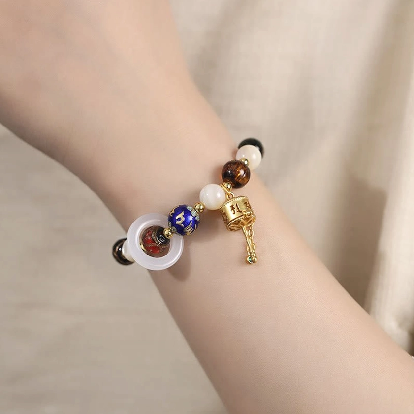 Om Mani Padme Hum prayer wheel bracelet worn on wrist, showing white jade ring and spiritual charm details