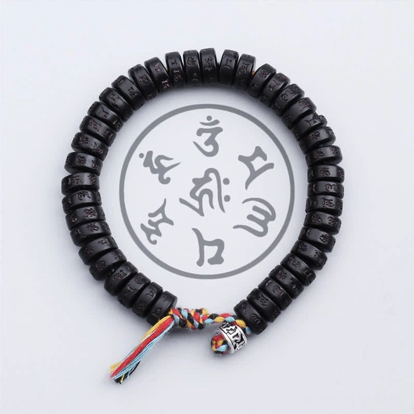 Close-up overhead view of Om Mani Padme Hum mantra bracelet showing engraved Sanskrit mantras on flat black coconut shell beads