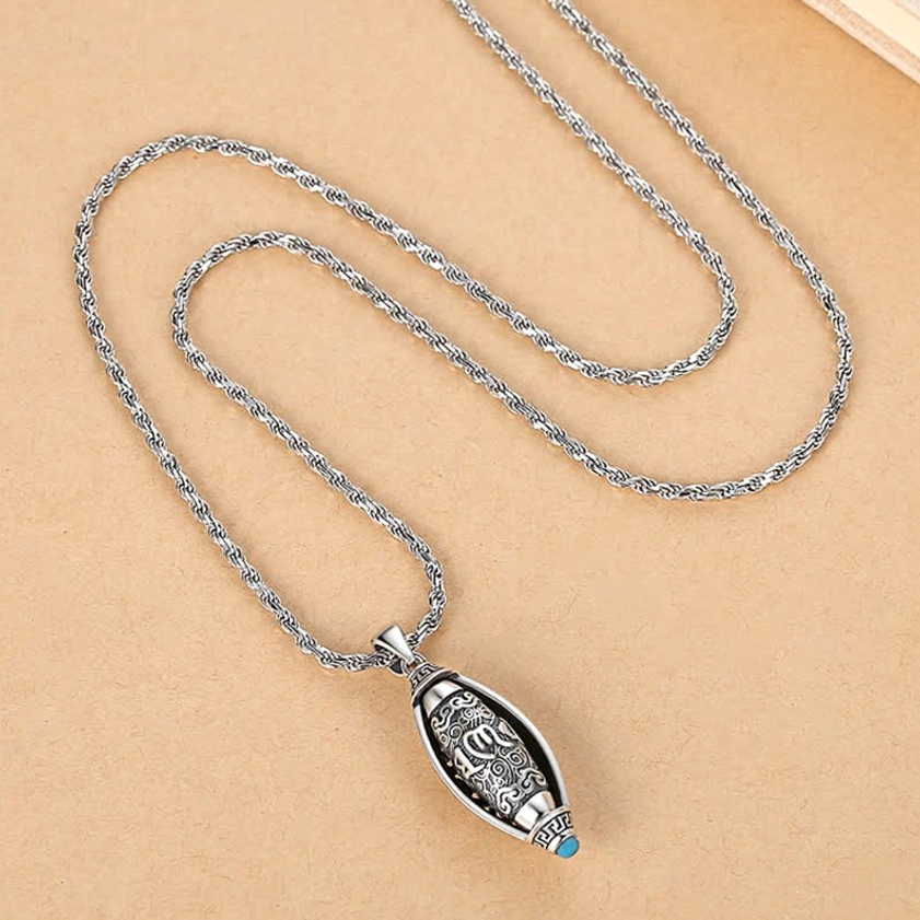 Om Mani Padme Hum mantra necklace flat lay showing full pendant design with Sanskrit carving, twisted rope chain, and blue stone accent stone