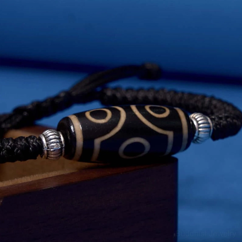 One-eye dzi bead bracelet flat lay front view displaying single eye motif with black cord