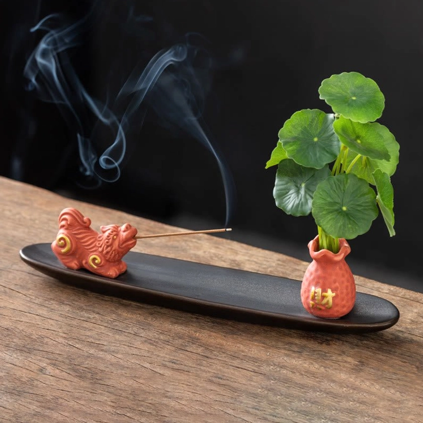 Orange Pixiu Buddhist wealth incense burner with red figurine, vase, penny grass and curling incense smoke
