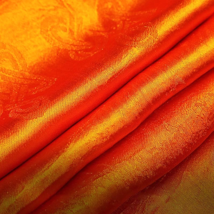 Gradient orange-yellow sacred khata fabric with embossed jacquard pattern and shiny ribbed weave close-up detail