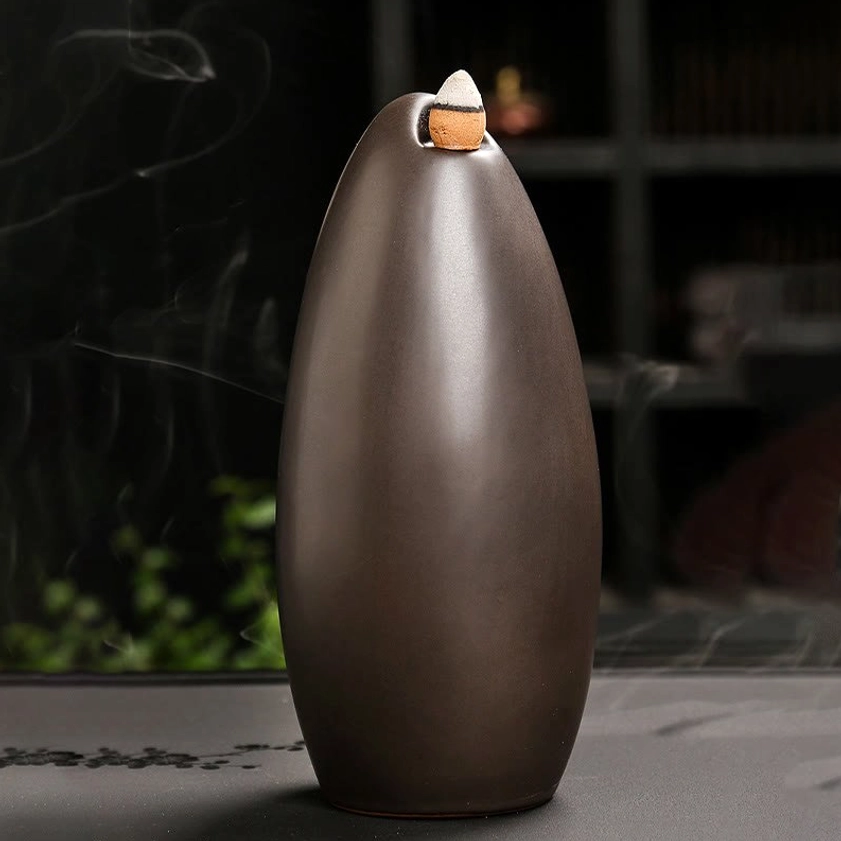 Oval shaped Buddhist ceramic backflow incense burner with smooth silhouette and flowing waterfall smoke demonstration