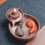 Handcrafted purple clay ox incense burner with dual slots top view, showing ceramic ox figurines and mill-style design on wooden table