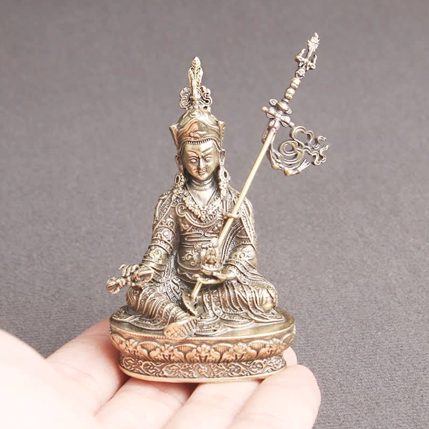 Padmasambhava Buddha statue held in hand showing compact size, two-tone bronze and copper finish, scale reference