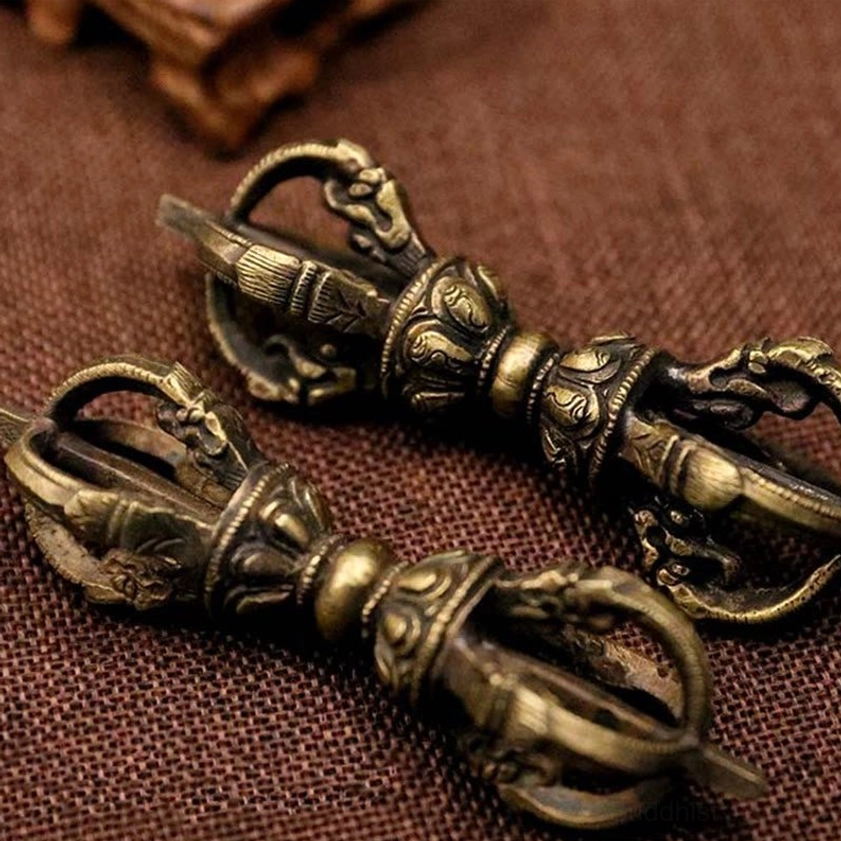 Pair of longer bronze five-prong vajra dorjes in angled flat lay view, demonstrating identical hand-carved styling