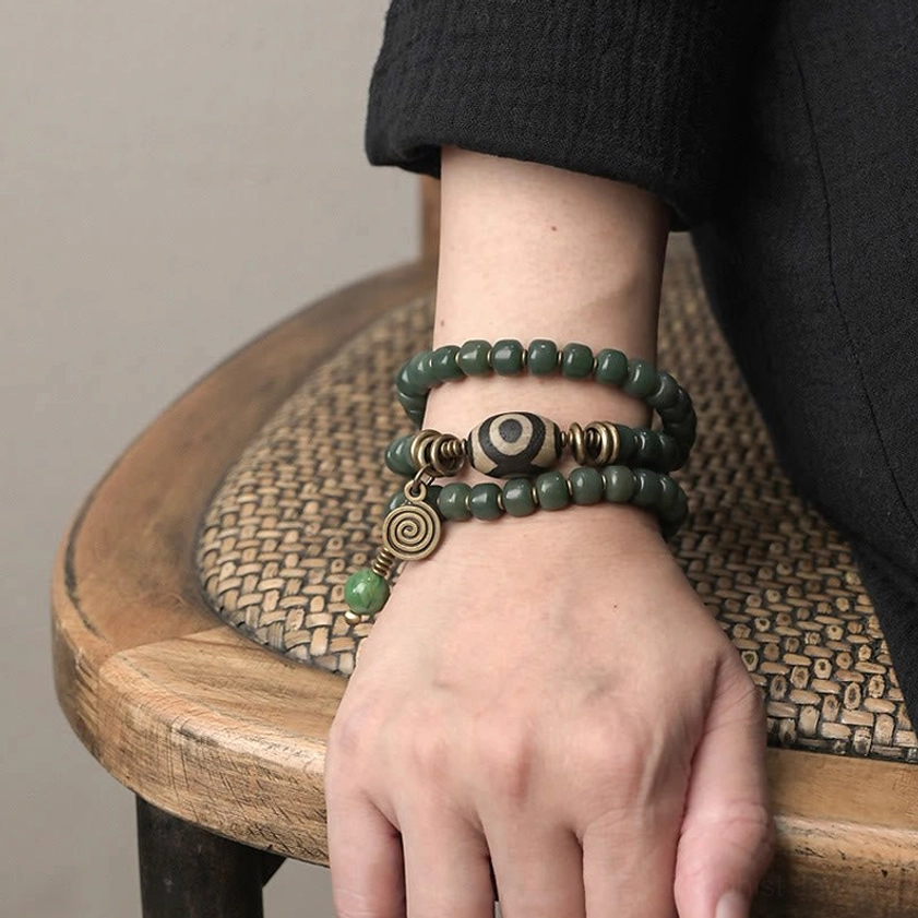 Both wrists wearing matching triple wrap bodhi dzi bracelets with full vintage bronze hardware