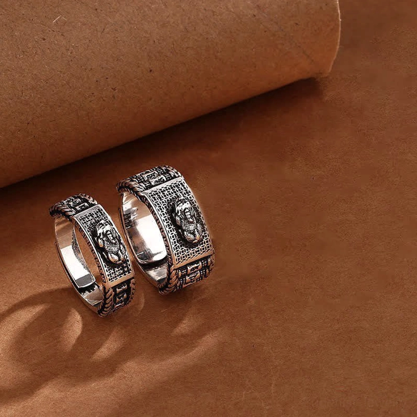 Pair of matching Pixiu prosperity rings - flat lay close-up featuring two vintage silver rings with traditional Buddhist embossed patterns and open design