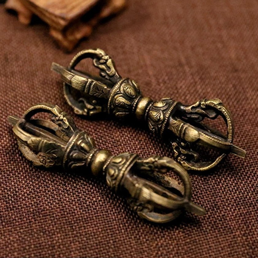 Pair of short bronze five-prong vajra dorjes displayed overhead, showing matching antique design and symmetric carvings