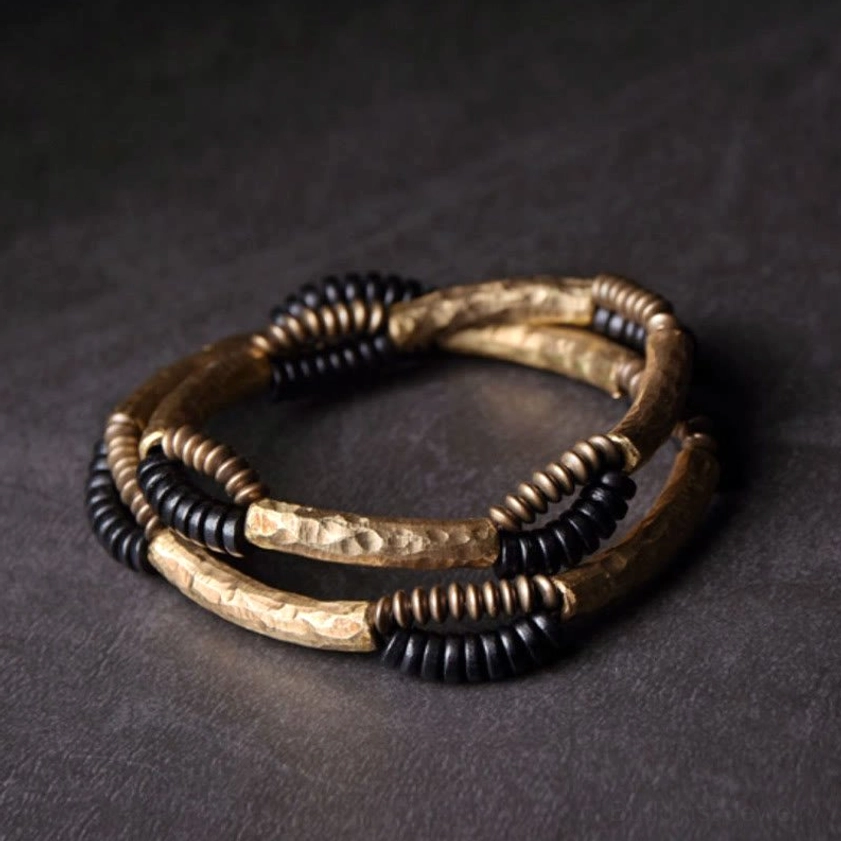 Two intertwined handmade ebony wood copper Buddhist bracelets flat lay display showing mixed metal and wood tones