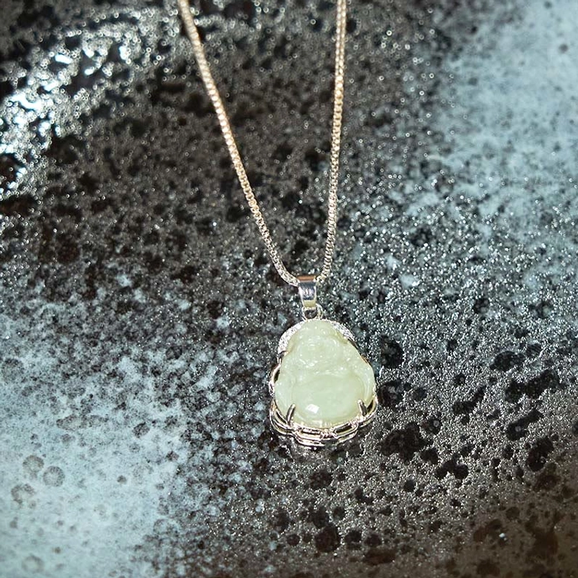 Off-white pale green Hetian jade Buddha pendant with carved details and sparkling crystal stone border, angled overhead shot - authentic Buddhist pendant for spiritual practice