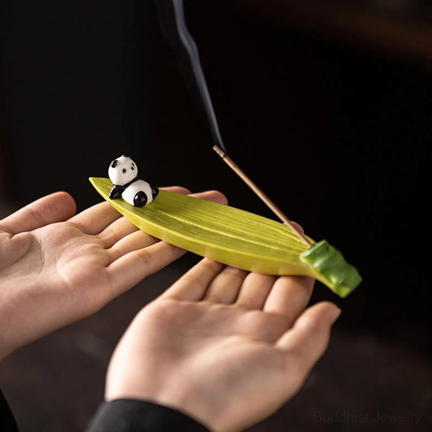Handcrafted ceramic panda on bamboo leaf incense holder held in hands, low view showing green ceramic detail