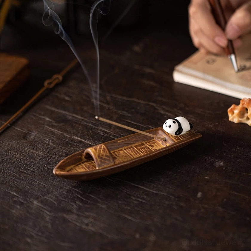 Top-down view of ceramic panda boat incense holder on study desk with burning incense, close-up detail