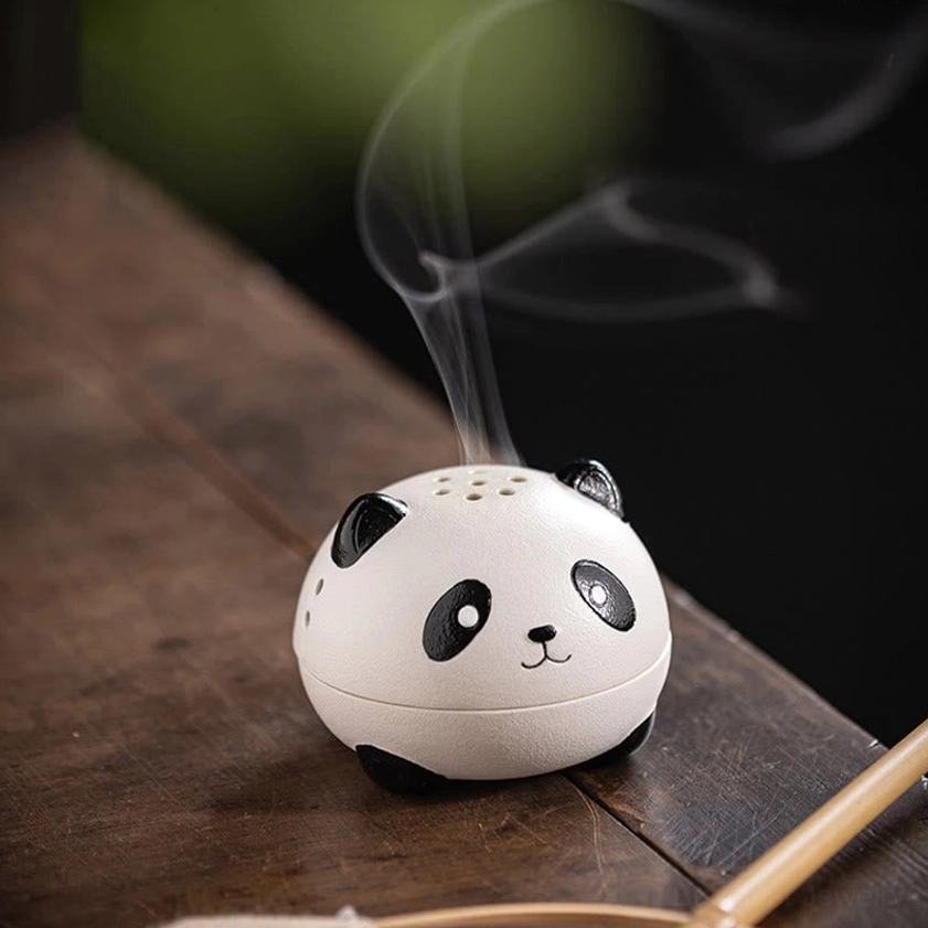 Front three-quarter view of panda ceramic incense holder on wooden tea desk, showcasing smooth matte ceramic texture and rising incense smoke