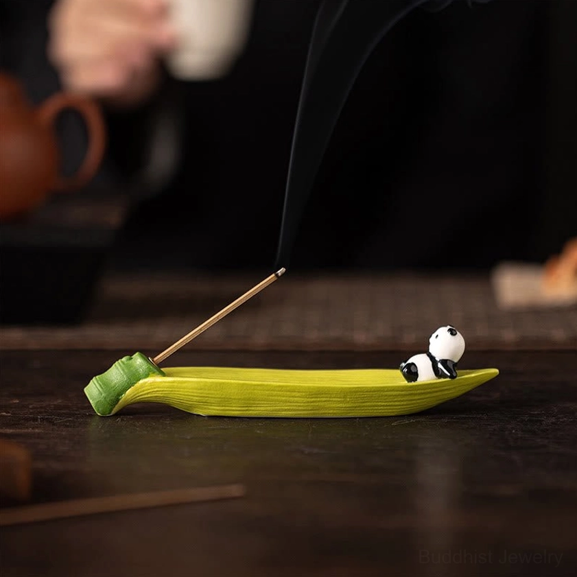 Ceramic panda on bamboo leaf incense holder with thick rising smoke, dim tea scene on dark background