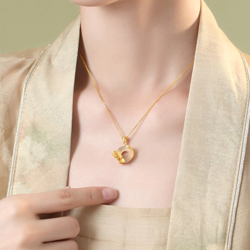 Model wearing sterling silver chalcedony lotus necklace with hand pointing to pendant on chest