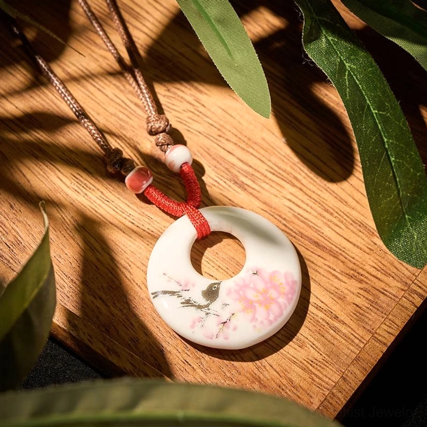 Peach blossoms ceramic pendant necklace overhead view on wooden table with artistic styling