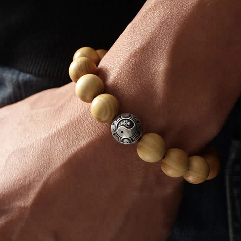 Woman wearing peach wood Buddhist bracelet with yin yang charm on wrist showing everyday styling