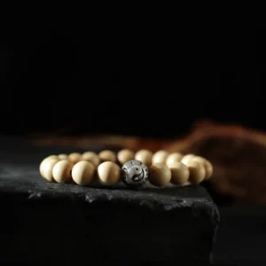 Peach wood and cinnabar Buddhist bracelet with yin yang and bagua charm beads displayed on black background