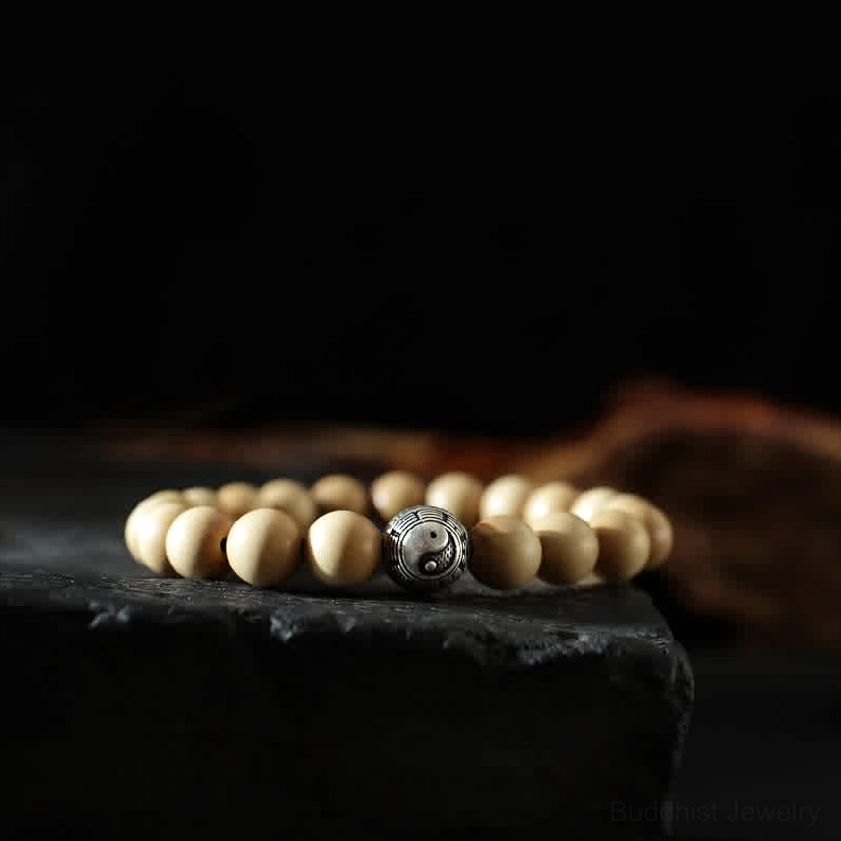 Peach wood and cinnabar Buddhist bracelet with yin yang and bagua charm beads displayed on black background