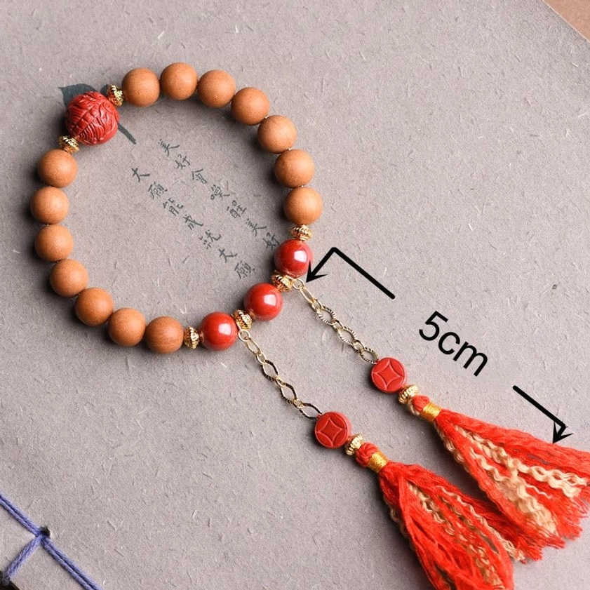 Peach wood and red cinnabar bracelet with dual red tassels and size marking on Chinese calligraphy paper background